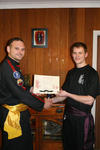 Master Bellchambers presents a certificate for Purple Sash to Mitchell