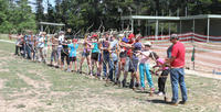 Fire Dragon students, friends and family at the Canberra Archery Club range, and with bows and arrows.